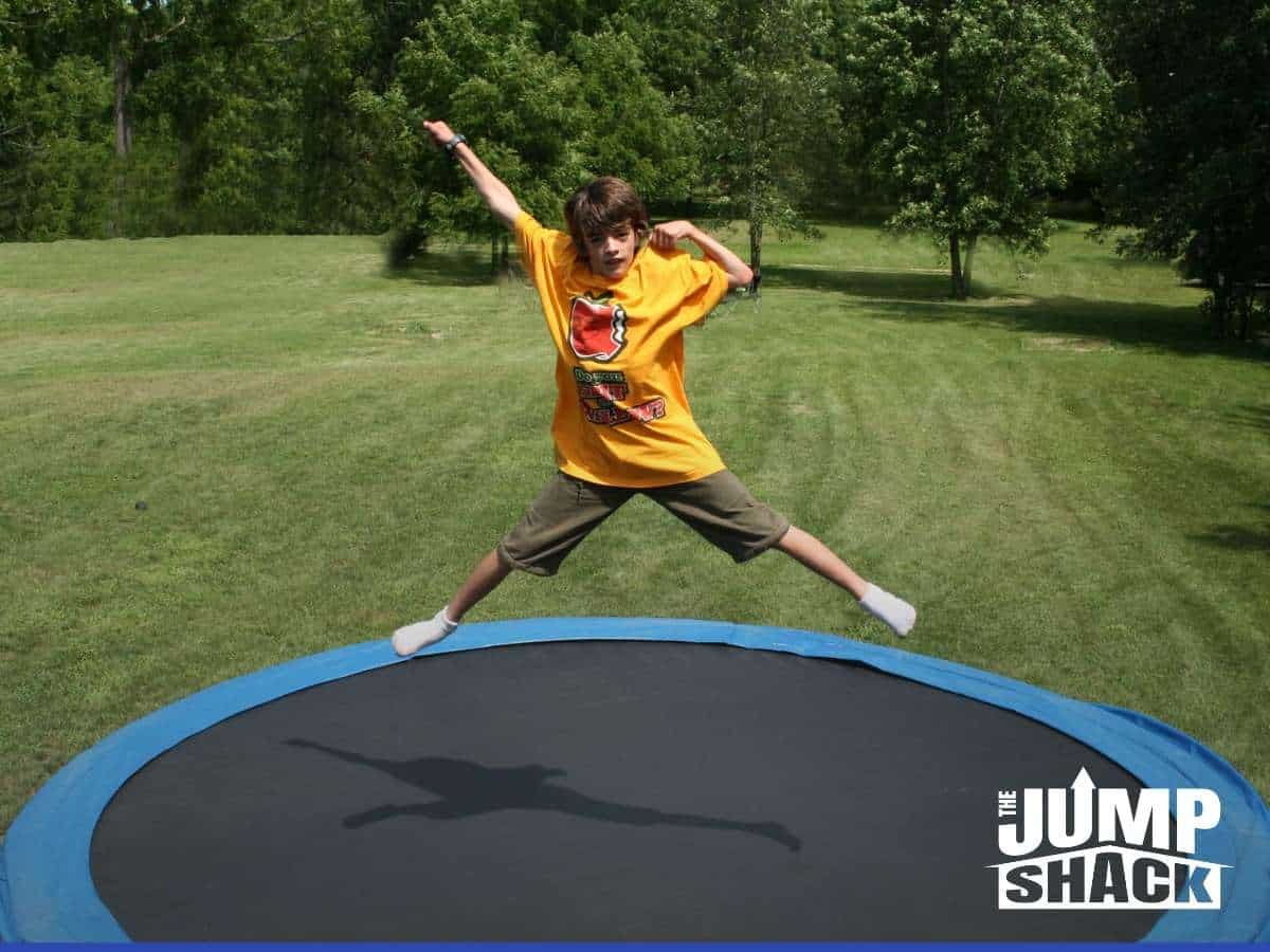 A Kid jumping in a in-ground trampoline